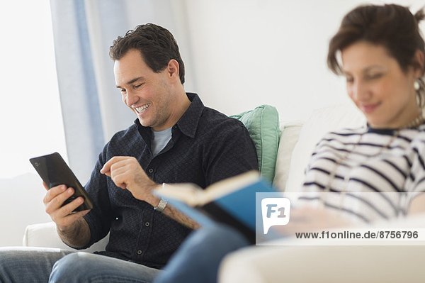 Couple sitting on sofa  man using digital tablet