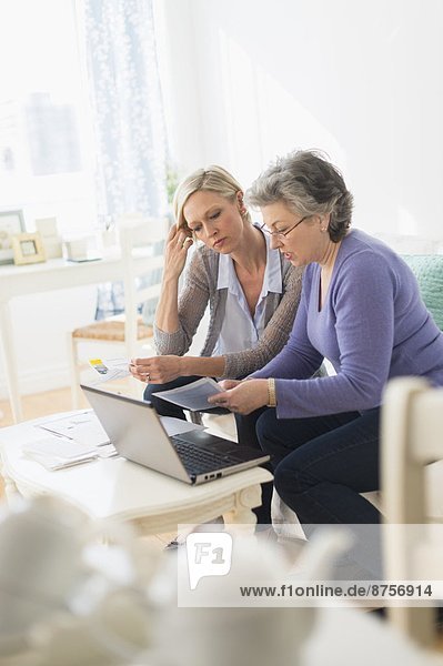 Two mature women paying bills via internet