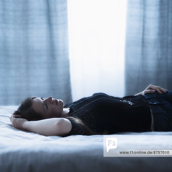 Portrait of beautiful woman lying down on bed