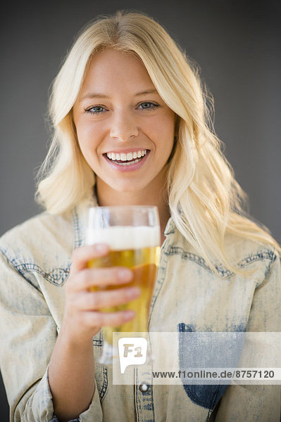 Portrait of young woman holding glass of beer