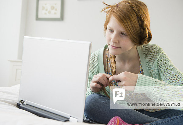 Girl (12-13) using laptop