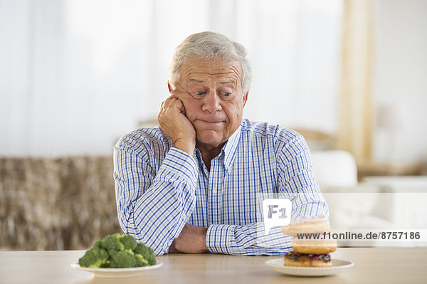 Portrait of senior man looking at doughnut