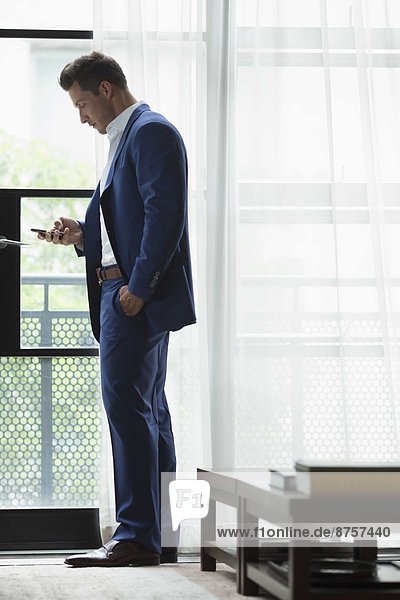 Young businessman standing inside and text messaging