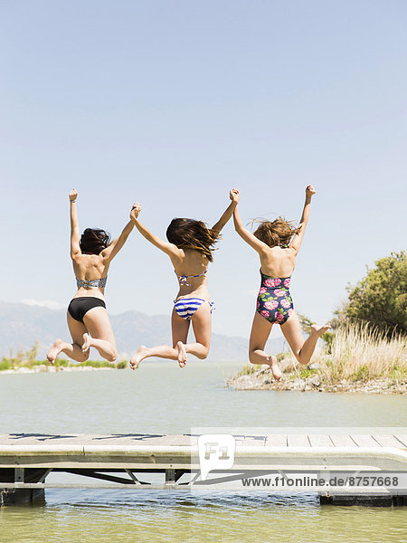 Three women jumping into lake