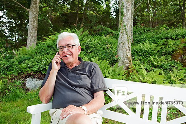 Senior man on bench talking via cell phone  Grundsund  Bohuslan  Sweden