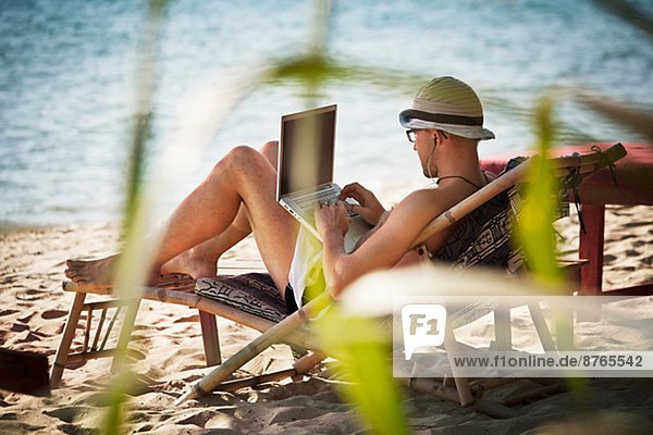 Man on beach using laptop