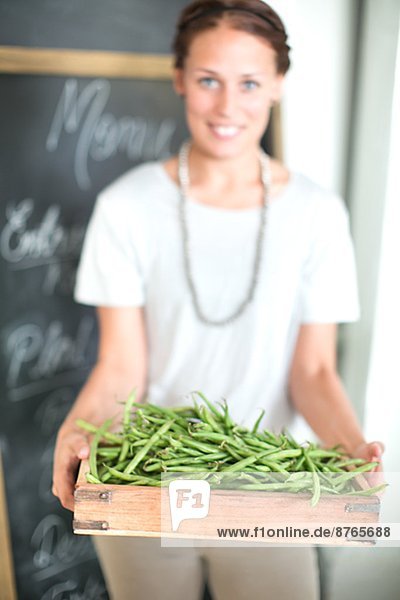 Woman holding green beans in wooden box