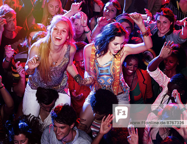 Männer mit jubelnden Frauen auf den Schultern in der Menge beim Musikfestival