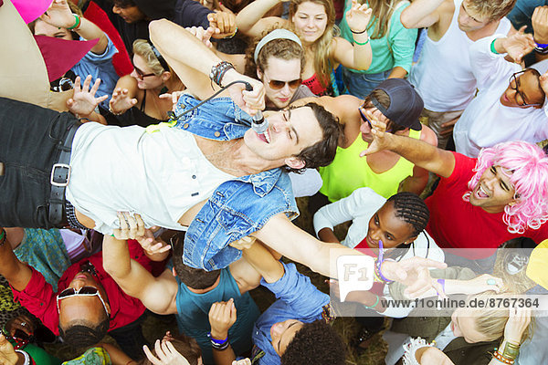 Performer with microphone crowd surfing at music festival