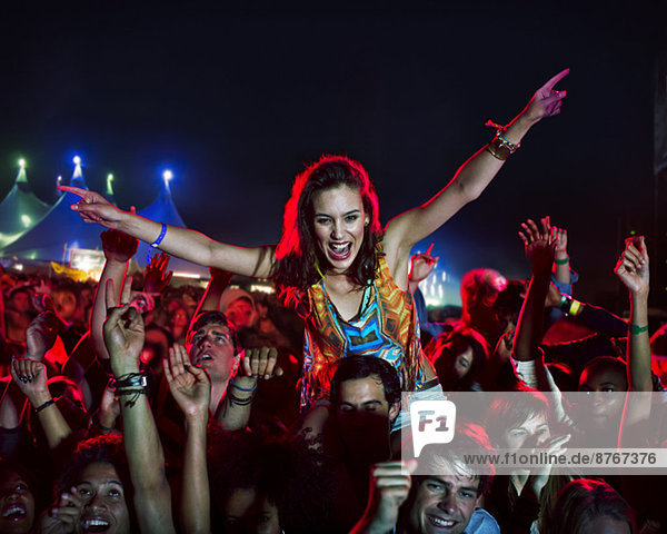 Cheering woman on manÍs shoulders at music festival