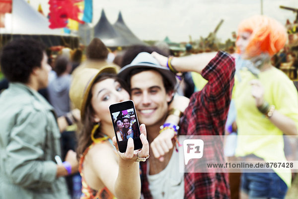 Couple taking self-portrait with camera phone at music festival