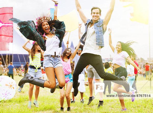 Portrait of enthusiastic friends jumping and dancing at music festival
