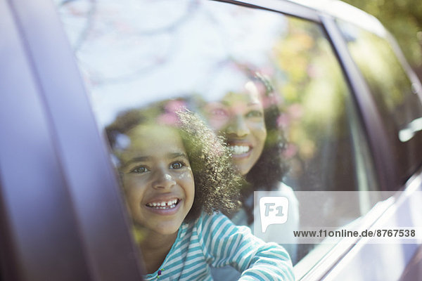 Glückliche Mutter und Tochter schauen aus dem Autofenster
