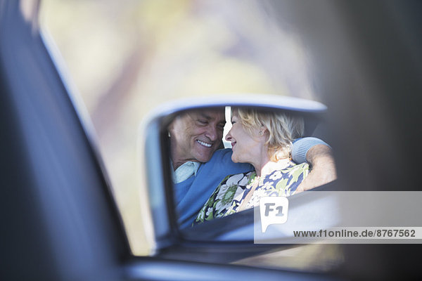 Seitenspiegelreflexion der Paarumarmung im Auto