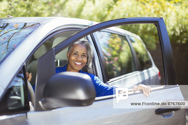 Portrait of confident senior woman getting out of car