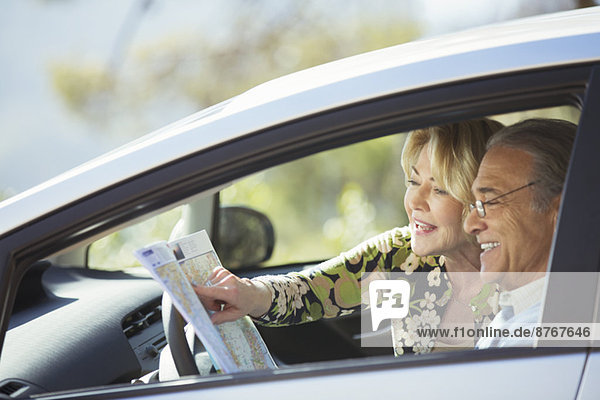 Seniorenpaar schaut auf die Karte im Auto