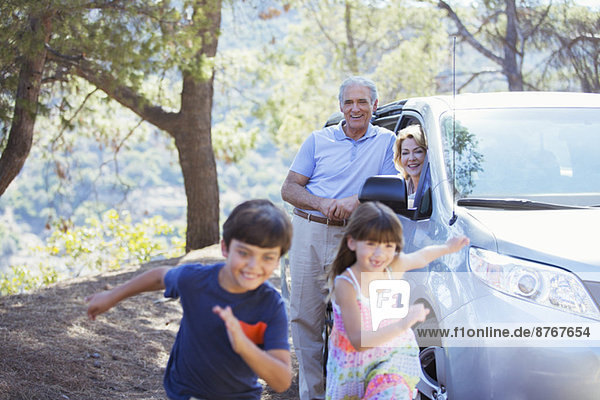 Großeltern beobachten Enkelkinder  die außerhalb des Autos rennen.