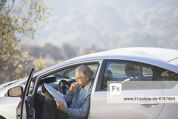 Senior man in car looking at map