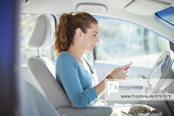 Frau SMS mit Handy im Auto