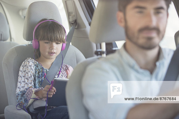 Mädchen mit Kopfhörer mit digitalem Tablett im Auto