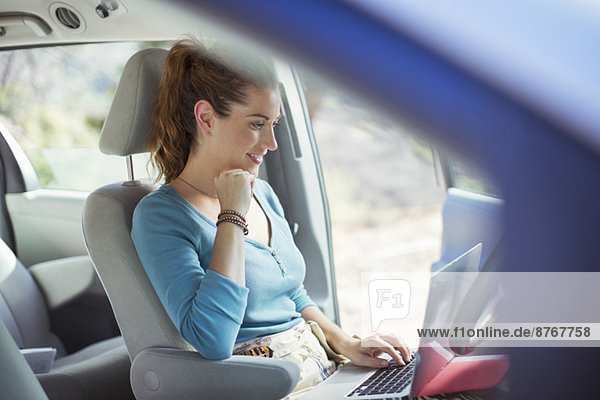 Woman using laptop in car
