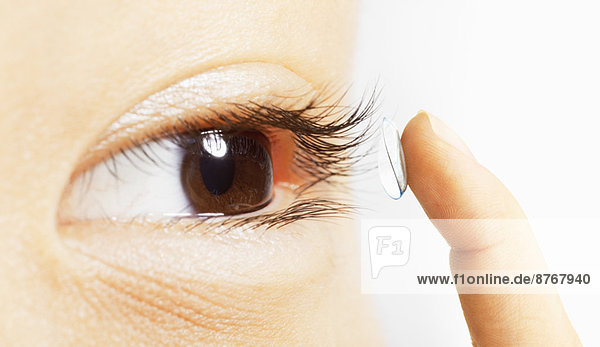 Extreme close up of woman putting contact lens in eye