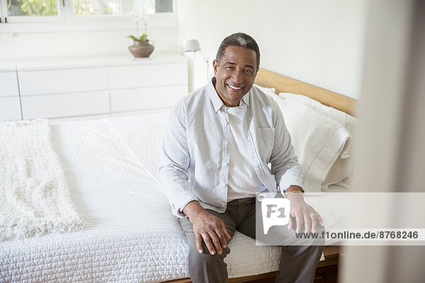 Portrait of smiling senior man sitting on bed