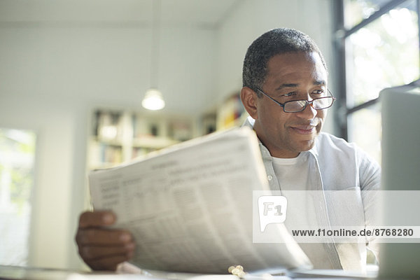 Senior Mann mit Zeitung mit Laptop