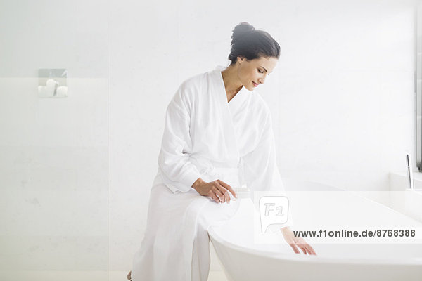 Frau im Bademantel beim Vorbereiten des Bades