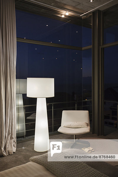 Lampe und Stuhl in der Ecke eines modernen Schlafzimmers