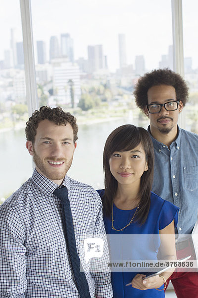 Portrait of confident business people at window overlooking city