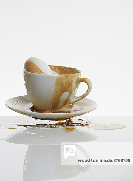 Weißer Kaffee vor weißem Hintergrund aus der Kaffeetasse spritzend