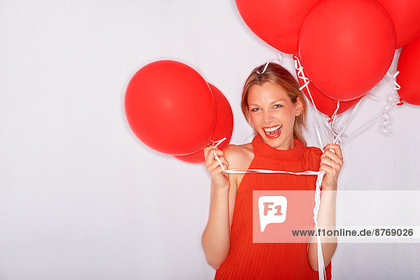 Excited young woman holding red balloons