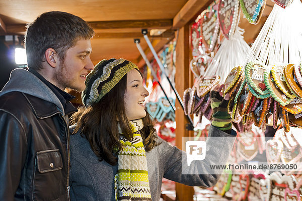 Germany  Berlin  young couple watching offerings at Christmas market