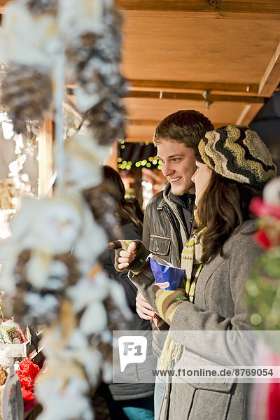 Germany  Berlin  young couple watching offerings at Christmas market