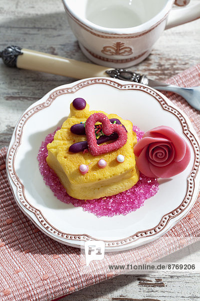 Dekorierte Muffinmarzipanblüte und rosa Zucker auf dem Teller