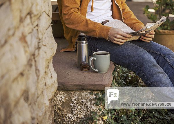 Young man sitting on steps having coffee break  partial view