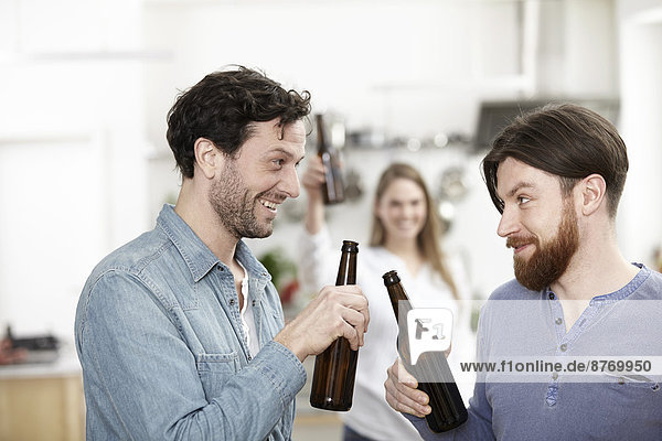 Friends in kitchen drinking beer