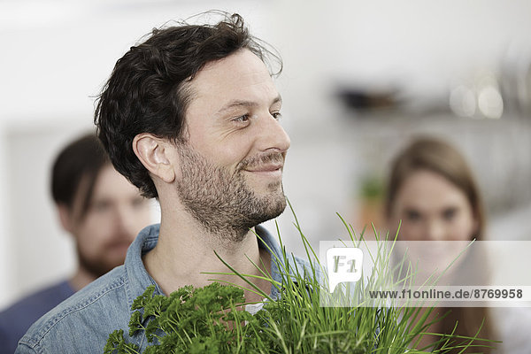 Smiling man with herbs in kitchen
