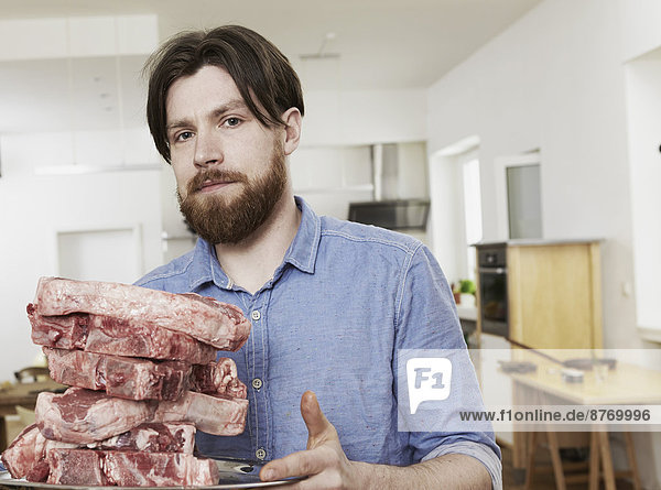Man in kitchen with raw steaks
