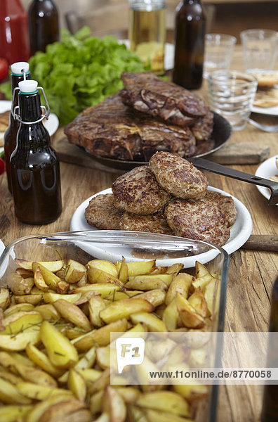 Dish with potatoes  steaks and meatballs on wooden table