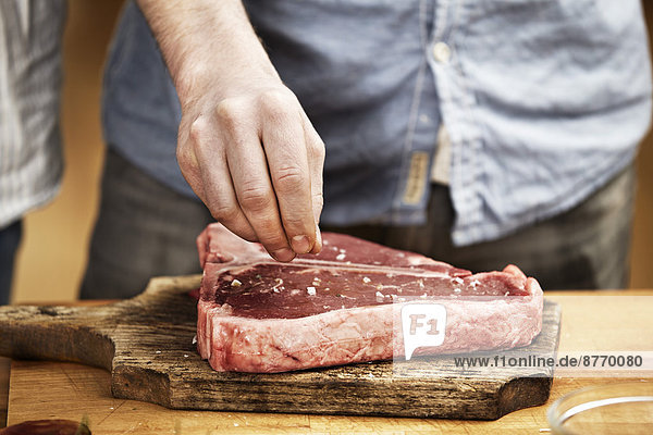 Mann bereitet Steak in der Küche zu