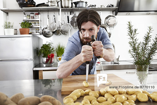 Mann beim Kartoffelspießen in der Küche