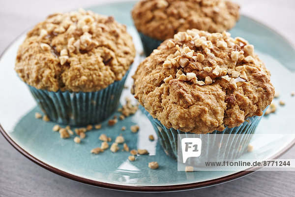 Teller mit drei Haferflocken-Muffins mit gebratenen und gehackten Mandeln