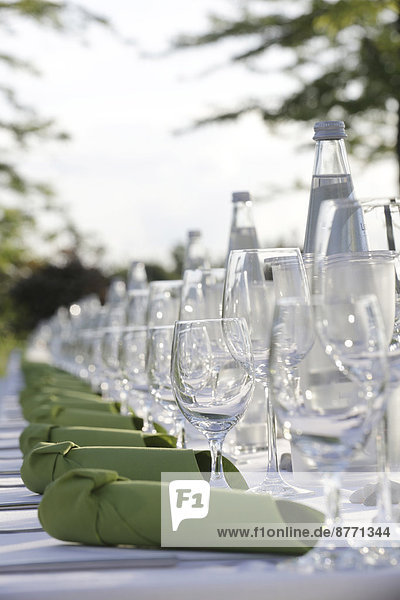 Festlich gedeckter Tisch mit grünen Servietten,  Wasserflaschen und Weingläsern