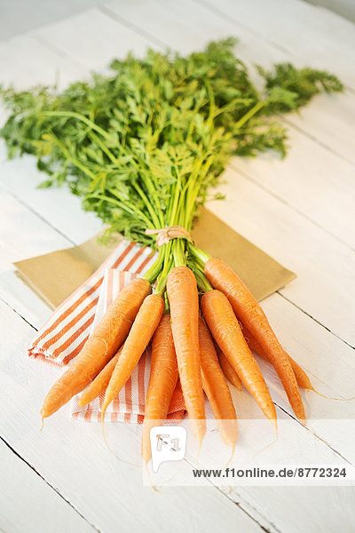 Bunch of organic carrots on cloth and white wooden table