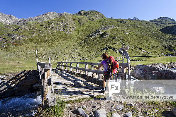 Female mountain climber at Timmelsalm alpine pasture crossing Timmlserbach stream  during the ascent to Müller Hut through the Passeiertal valley along the Timmelsjoch pass route  Alto Adige  Italy