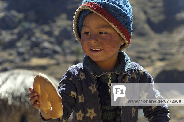 Indiojunge mit Brot in der Hand  bei Cusco  Anden  Peru