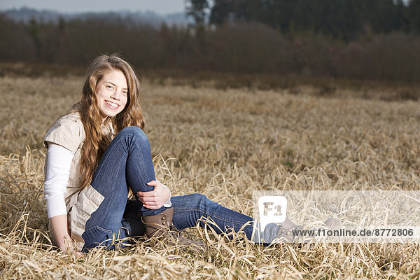 Portrait of smiling teenage girl sitting on field