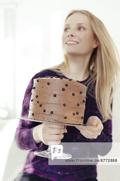 Junge Frau hält Kuchenstand mit Schokoladenkuchen
